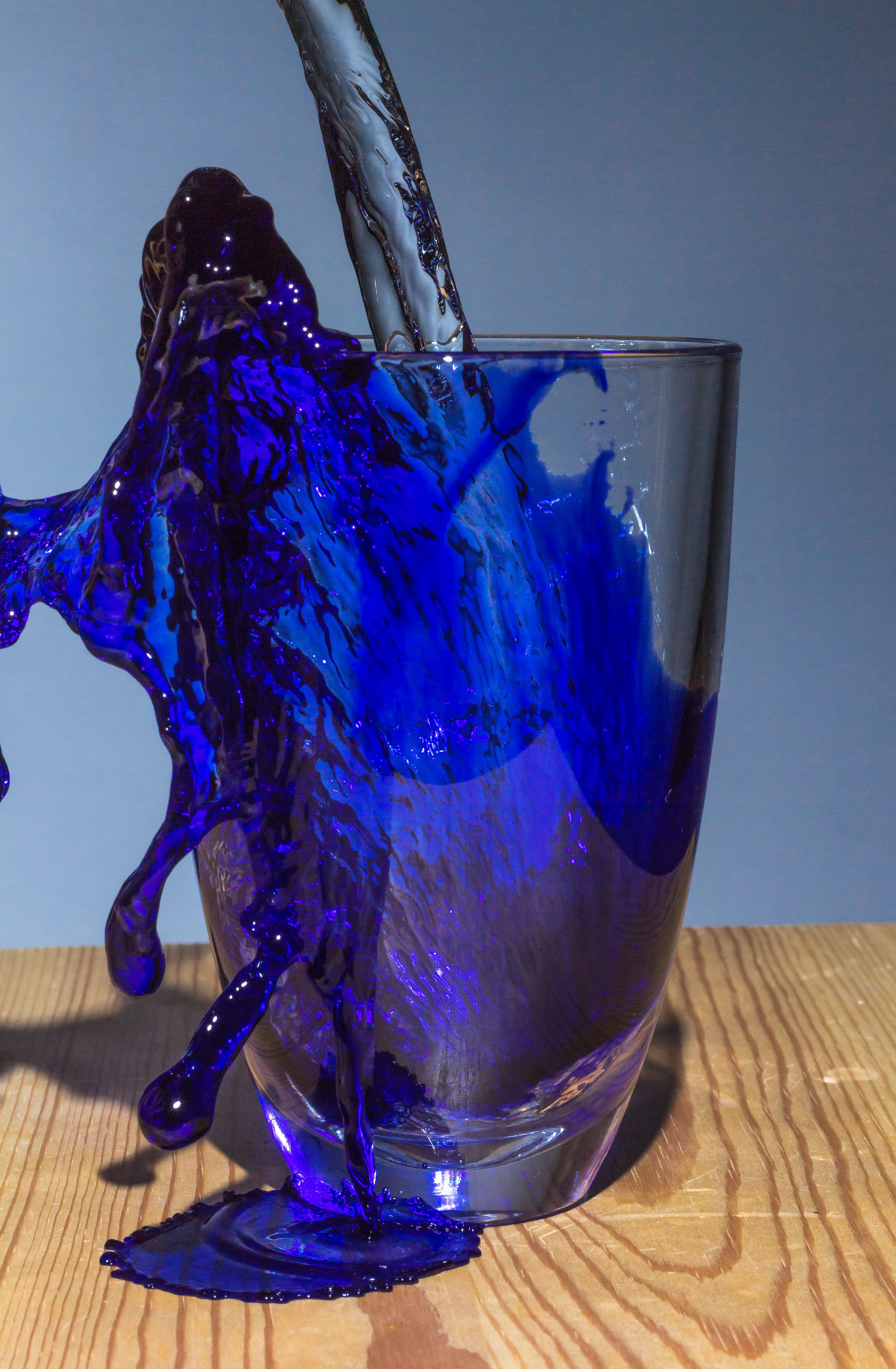 Clear water flowing into a glass and suddenly turning blue inside of the glass